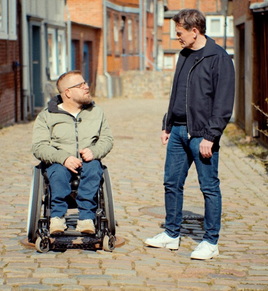 Daniel Schütz begleitet einen Menschen im Rollstuhl durch die Altstadt